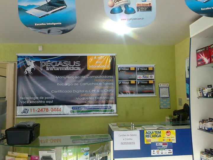 Faixa da Pegasus Informática na parede da loja, com a lista de serviços que inclui criação de sites